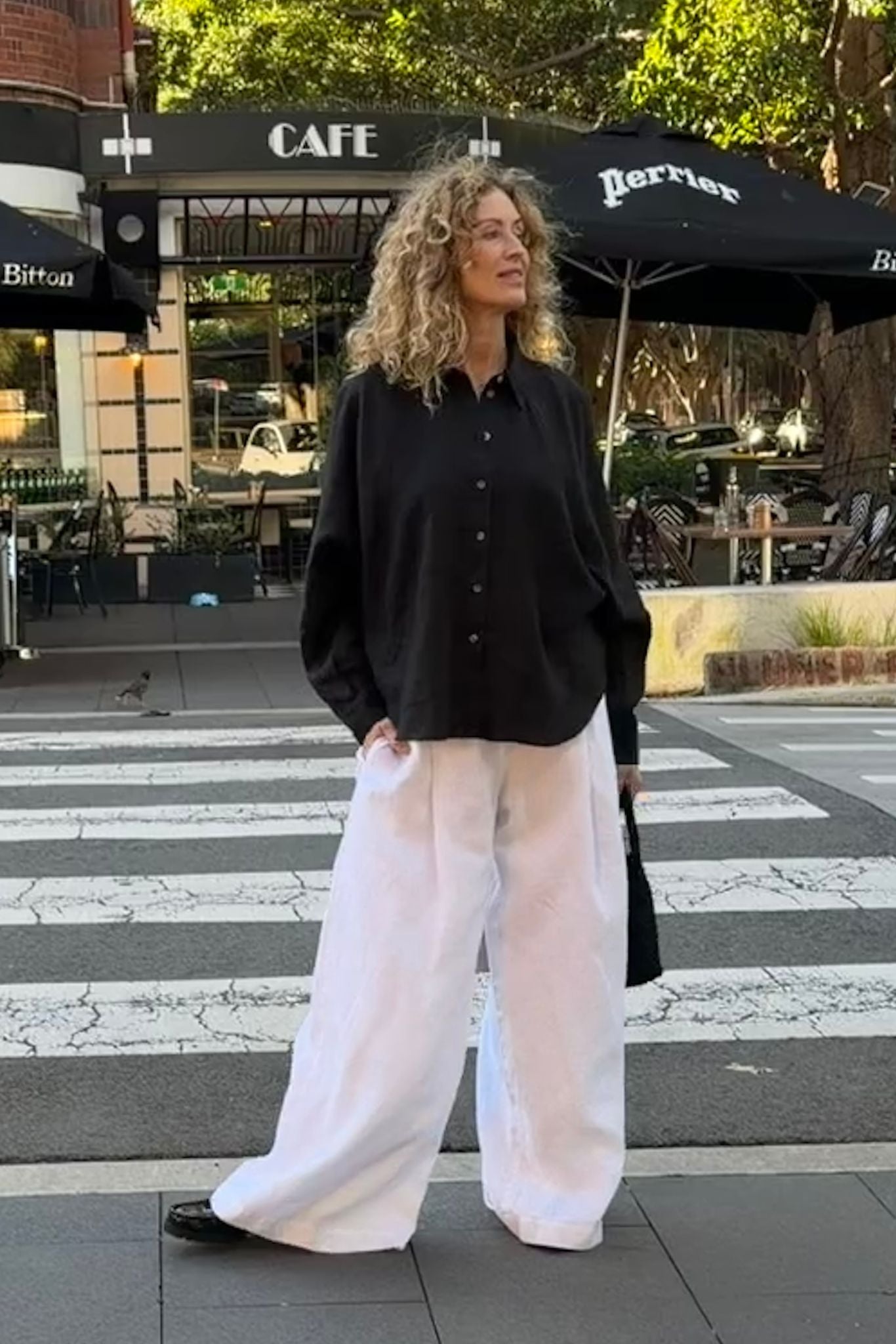 Eira black linen shirt with two-piece collar and natural flecked buttons worn with white aura pants