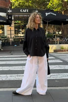 Eira black linen shirt with two-piece collar and natural flecked buttons worn with white aura pants